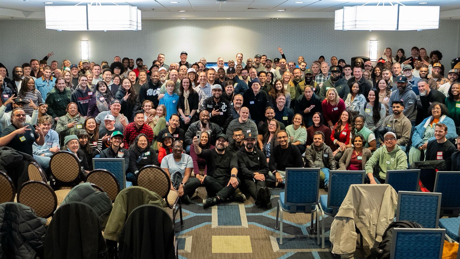 Attendees gathered for a group photograph in a hotel ballroom at a SubTo member meetup. Archive photograph, not this meetup.