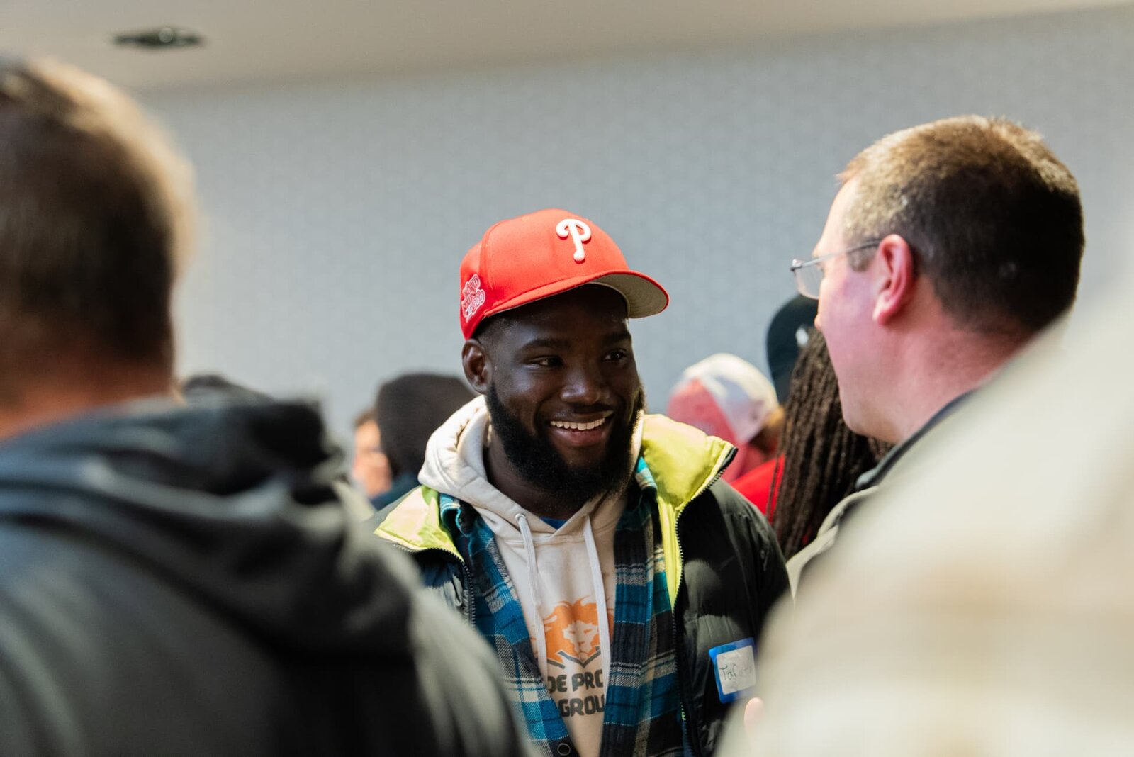 A member in a red cap talks with peers at a SubTo community gathering.